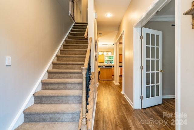 staircase with hardwood / wood-style flooring and ornamental molding