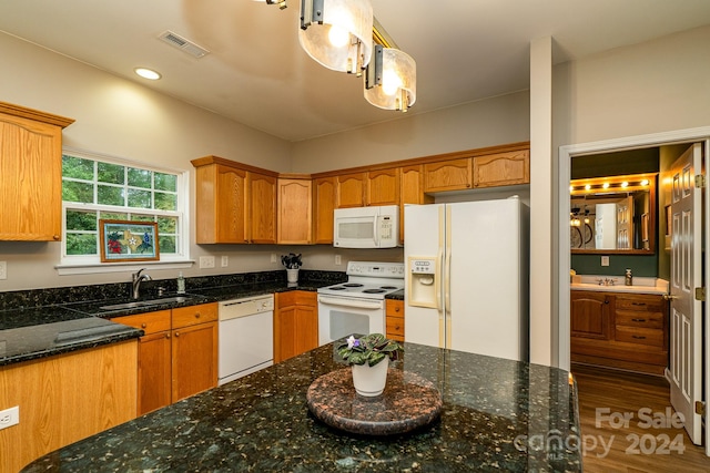 kitchen with pendant lighting, dark wood-type flooring, sink, white appliances, and dark stone countertops