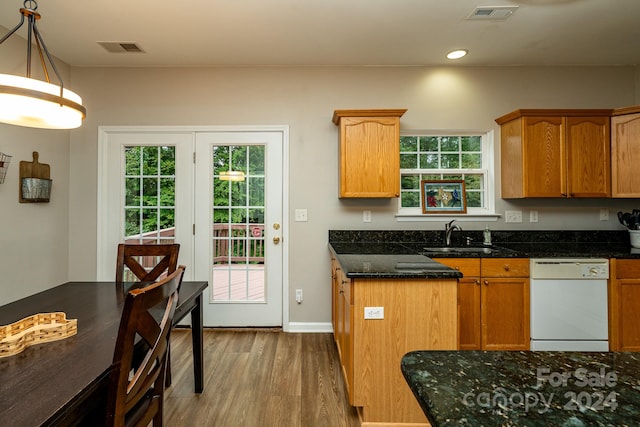 kitchen featuring sink, decorative light fixtures, dishwasher, hardwood / wood-style flooring, and dark stone counters