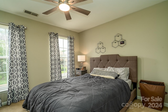 carpeted bedroom with multiple windows and ceiling fan