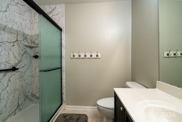 bathroom with vanity, a shower with shower door, toilet, and tile patterned flooring