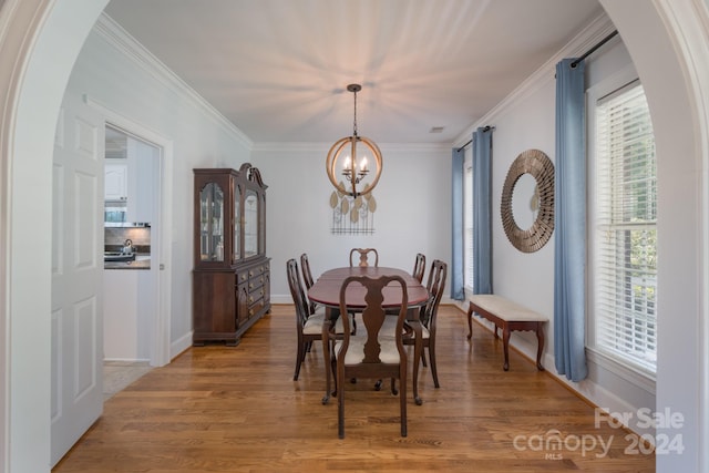 dining room featuring wood-type flooring, ornamental molding, and an inviting chandelier