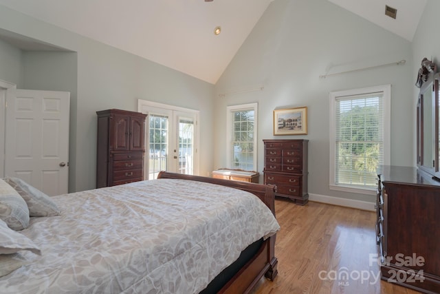 bedroom featuring access to outside, high vaulted ceiling, light hardwood / wood-style flooring, and french doors