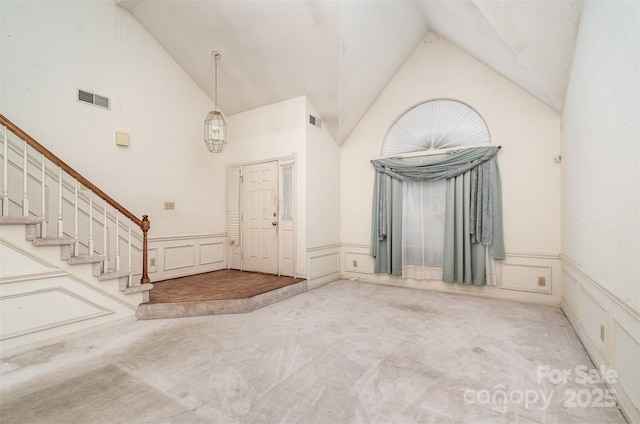 carpeted entryway featuring high vaulted ceiling