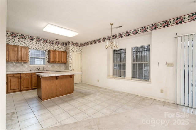 kitchen featuring decorative backsplash, a chandelier, a kitchen island, hanging light fixtures, and a breakfast bar area