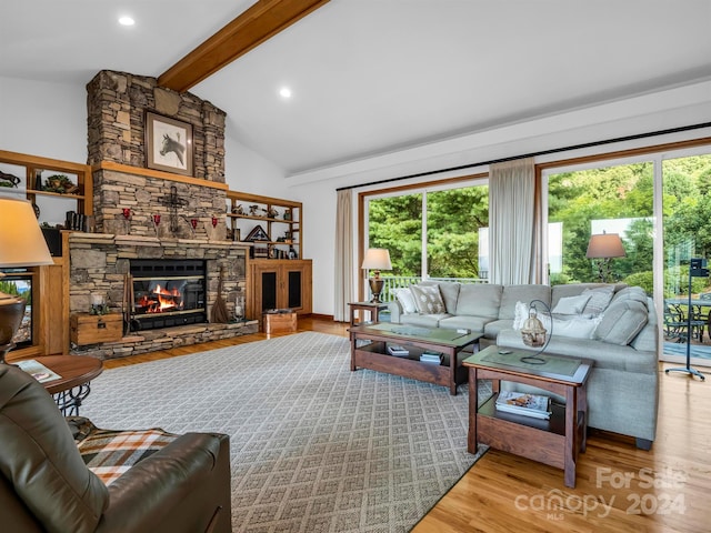 living room featuring light wood-type flooring, high vaulted ceiling, beam ceiling, and a stone fireplace