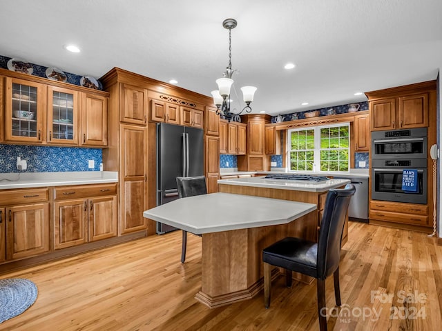 kitchen with backsplash, appliances with stainless steel finishes, light hardwood / wood-style floors, a kitchen bar, and a center island