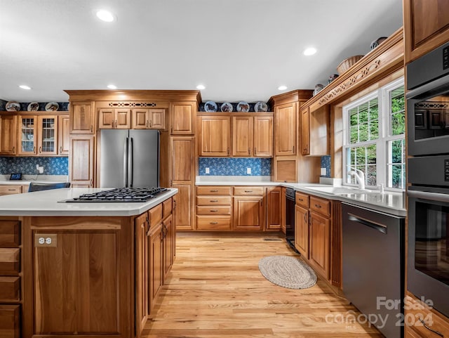 kitchen featuring light wood-type flooring, appliances with stainless steel finishes, sink, and decorative backsplash