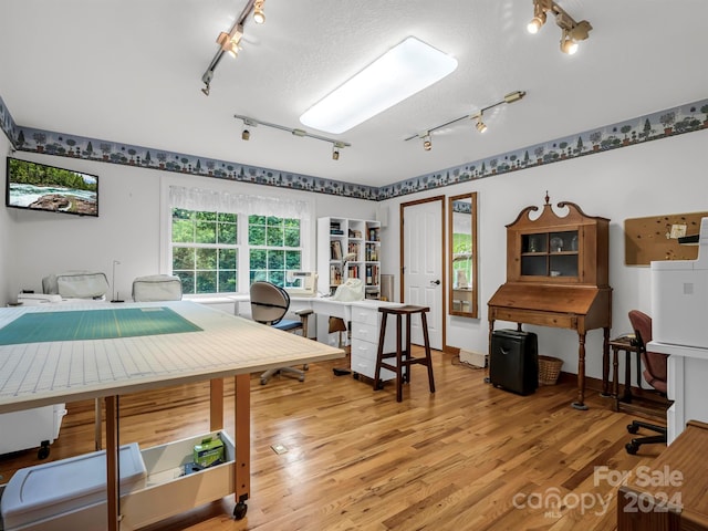 interior space featuring a textured ceiling, light wood-type flooring, and track lighting