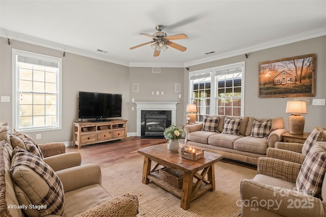 living room with ceiling fan, plenty of natural light, crown molding, and light wood-type flooring