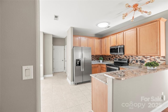 kitchen featuring light brown cabinets, appliances with stainless steel finishes, tasteful backsplash, light stone counters, and kitchen peninsula