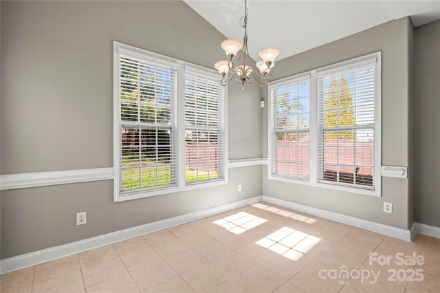 tiled empty room featuring a wealth of natural light, vaulted ceiling, and a notable chandelier