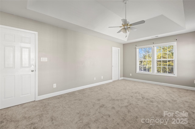 carpeted empty room with ceiling fan and a tray ceiling