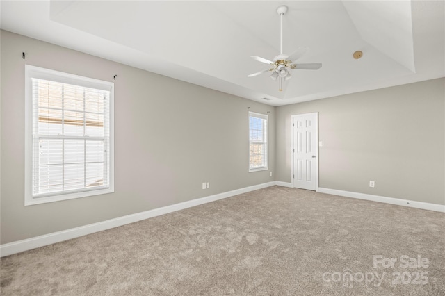 spare room with a tray ceiling, ceiling fan, and light colored carpet