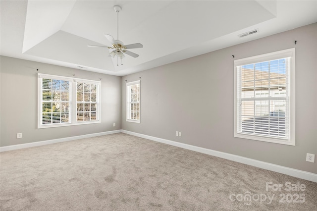 empty room featuring carpet, a raised ceiling, and ceiling fan