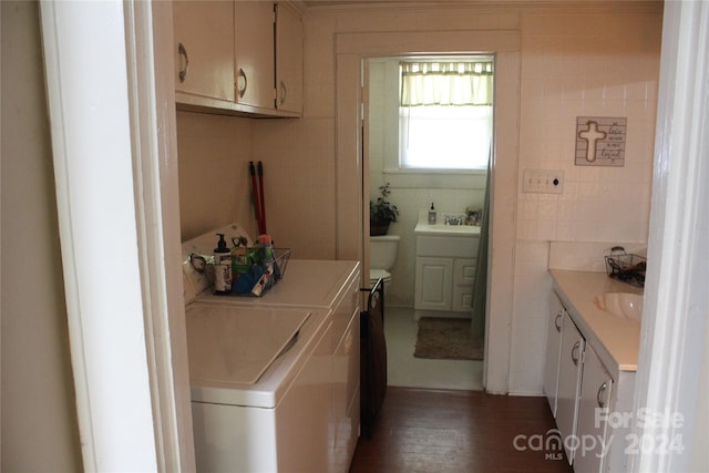 washroom with washing machine and clothes dryer, dark hardwood / wood-style flooring, and tile walls