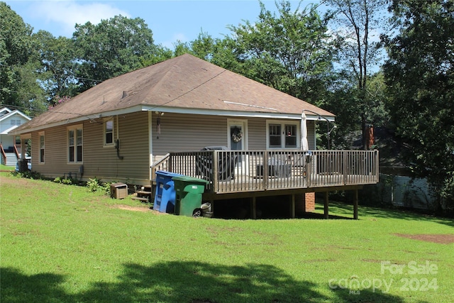 rear view of house featuring a lawn and a deck