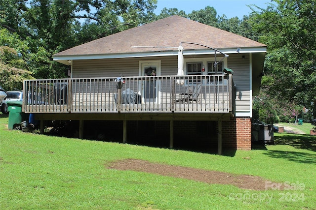 rear view of house featuring a lawn and a deck