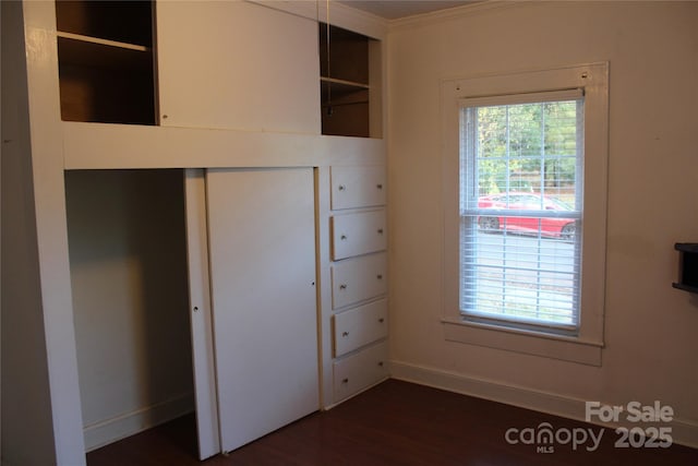 unfurnished bedroom with crown molding, dark hardwood / wood-style floors, and a closet