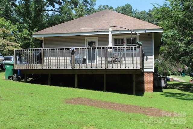 rear view of house featuring a wooden deck and a yard