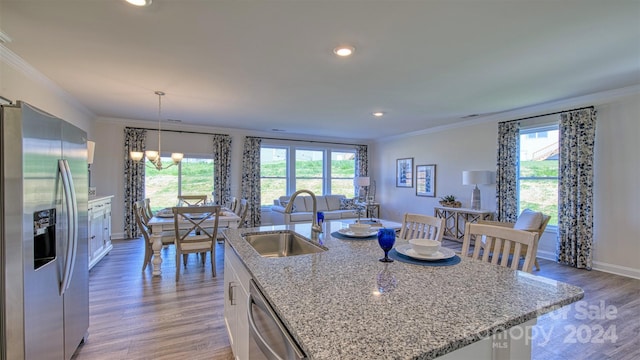 kitchen featuring a center island with sink, stainless steel appliances, white cabinets, decorative light fixtures, and sink