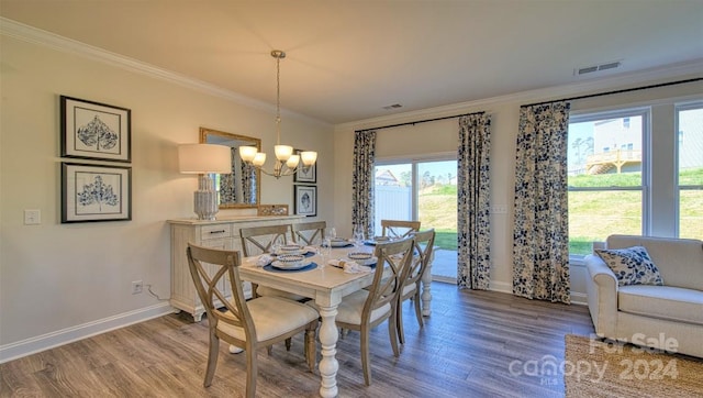 dining space with wood-type flooring, a chandelier, and crown molding