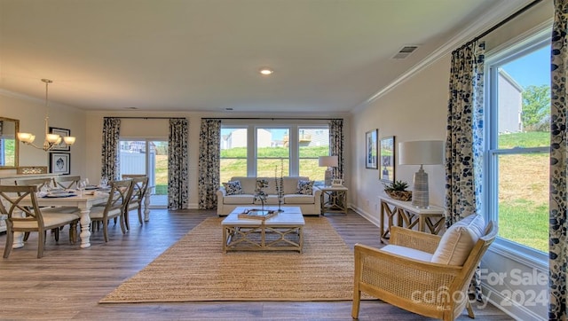 living room with hardwood / wood-style flooring, crown molding, and a notable chandelier