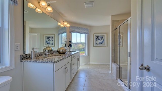 bathroom with toilet, tile patterned flooring, a shower with shower door, and vanity