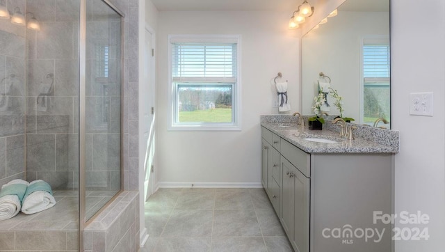 bathroom with tile patterned flooring, a shower with door, and double sink vanity