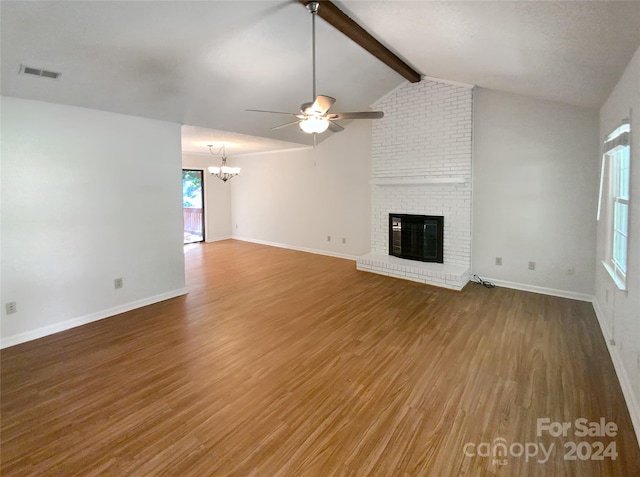 unfurnished living room featuring hardwood / wood-style floors, vaulted ceiling with beams, brick wall, and a fireplace