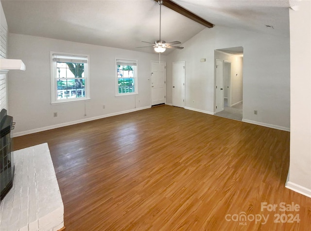 unfurnished living room with lofted ceiling with beams, hardwood / wood-style flooring, ceiling fan, and a brick fireplace