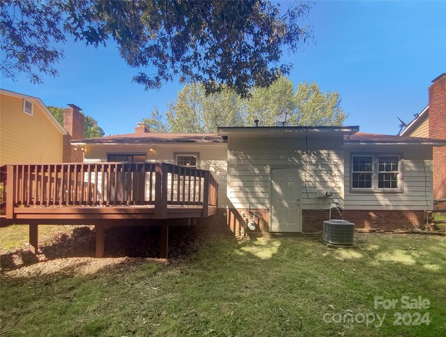 rear view of house featuring central AC unit, a deck, and a lawn