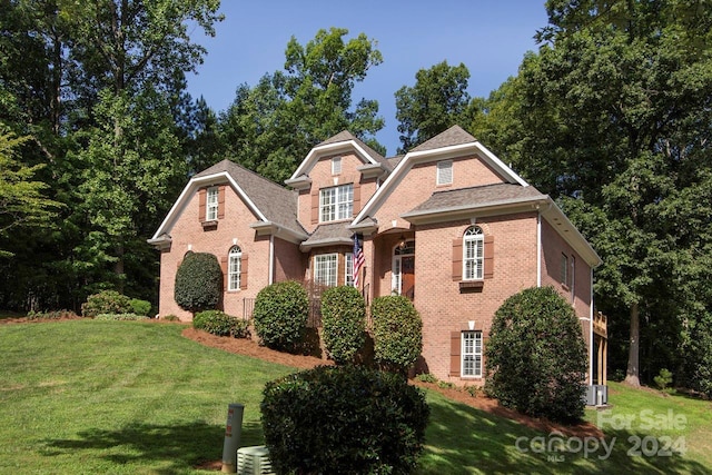 view of front of home with brick siding, a front lawn, and central air condition unit