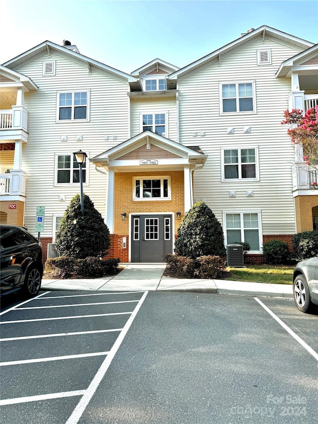 view of front of home featuring central air condition unit, uncovered parking, and brick siding