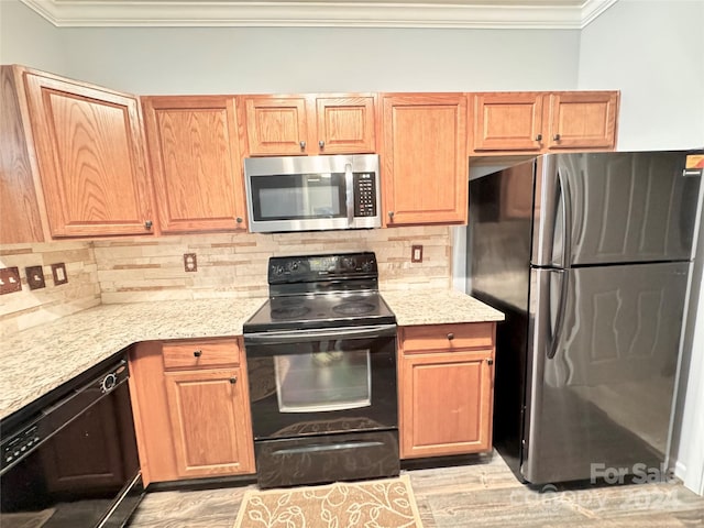 kitchen featuring black appliances, backsplash, light stone countertops, and crown molding