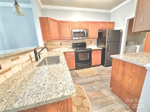 kitchen with washer and clothes dryer, appliances with stainless steel finishes, a sink, crown molding, and backsplash