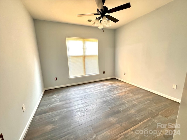 unfurnished room with a ceiling fan, wood finished floors, visible vents, and baseboards