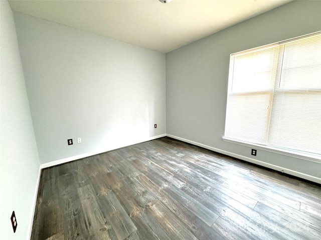 empty room featuring dark wood-type flooring and baseboards