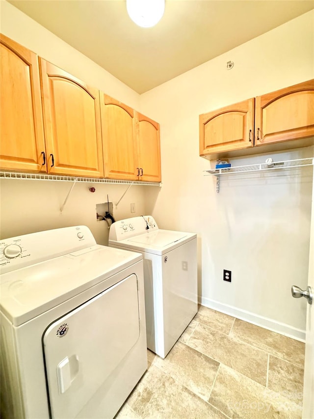 laundry area featuring baseboards, stone finish floor, cabinet space, and washer and dryer