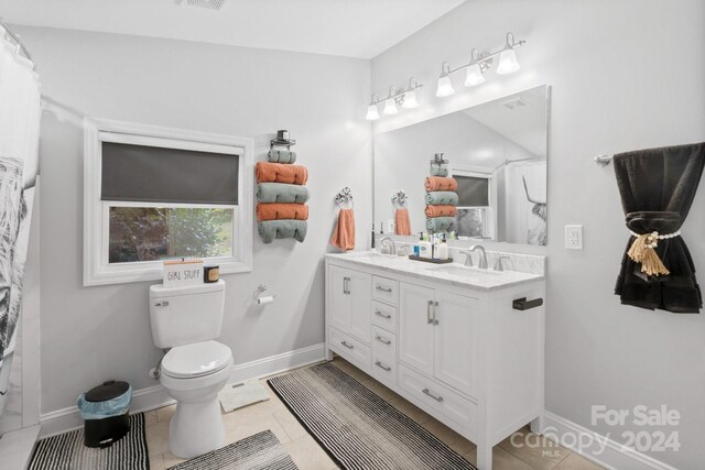 bathroom with toilet, double vanity, and tile patterned floors