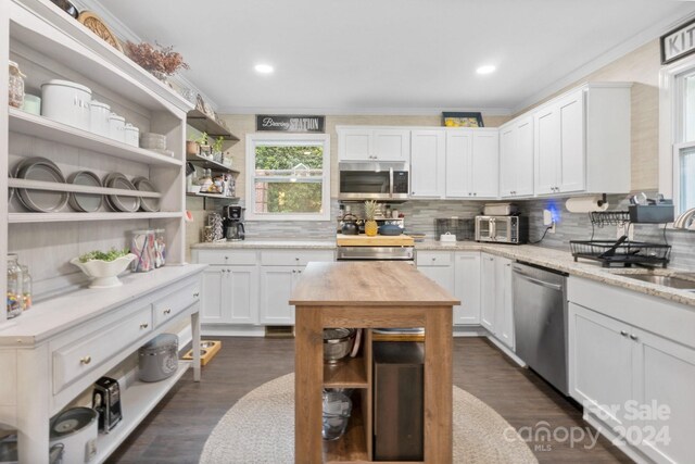 kitchen featuring white cabinets, dark wood-type flooring, stainless steel appliances, and decorative backsplash