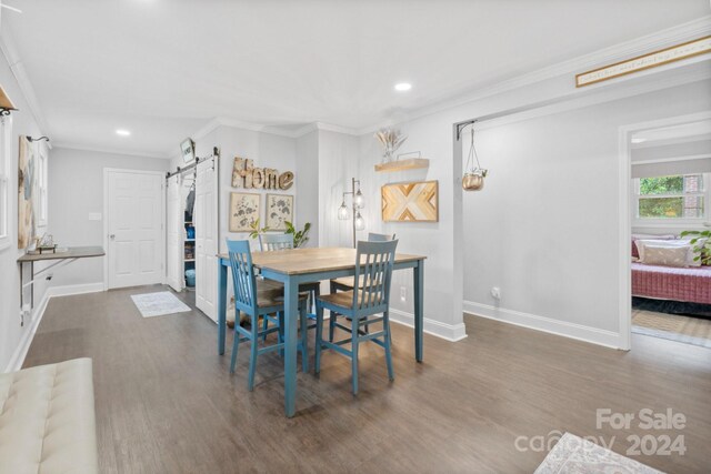 dining room with ornamental molding, dark hardwood / wood-style flooring, and a barn door