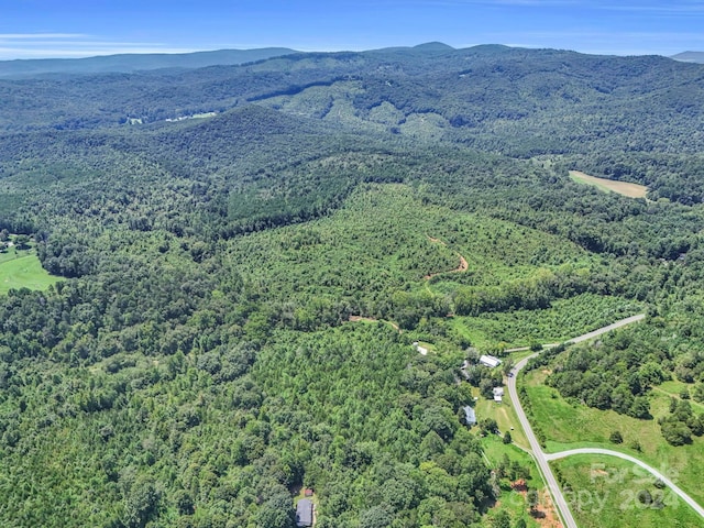 aerial view featuring a wooded view and a mountain view