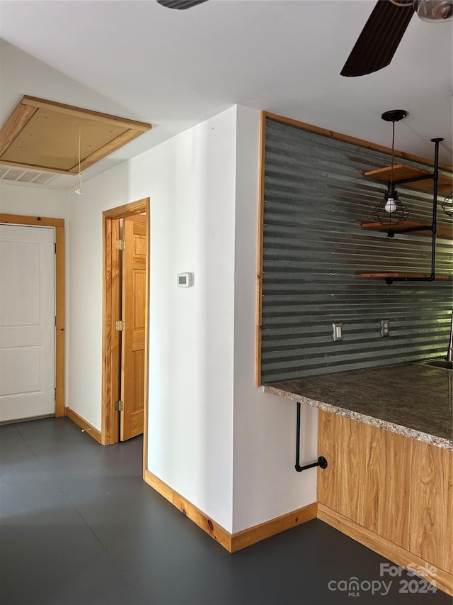 hall with attic access, concrete floors, and baseboards