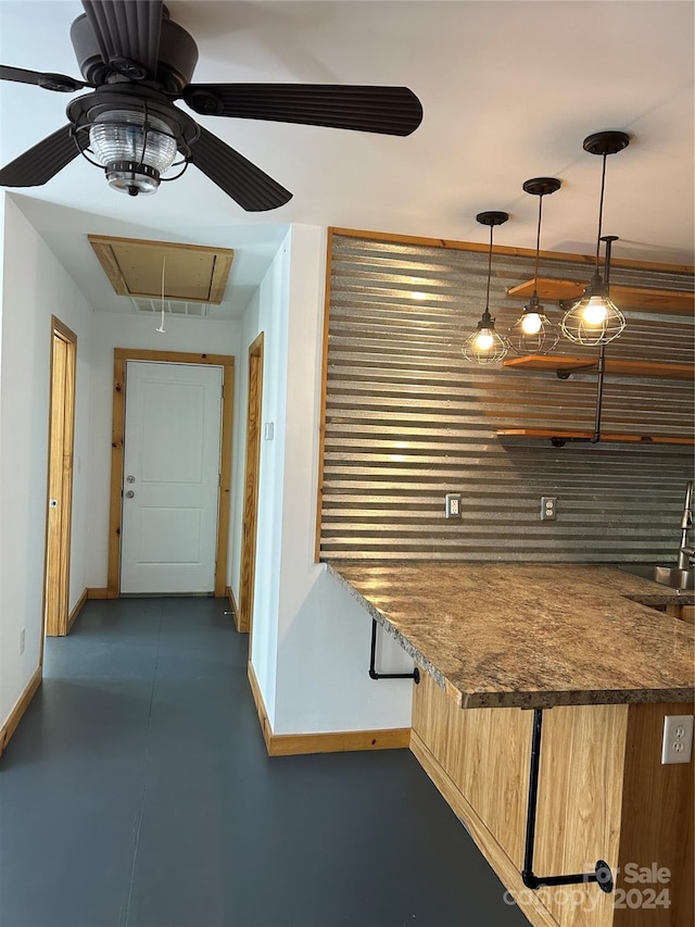 kitchen with finished concrete floors, a sink, baseboards, dark countertops, and pendant lighting