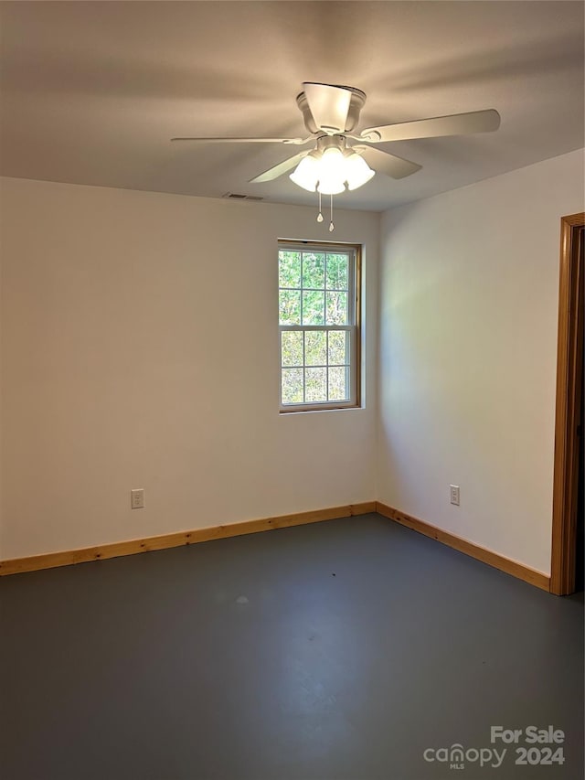 unfurnished room featuring visible vents, concrete floors, baseboards, and ceiling fan