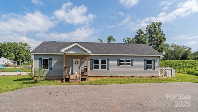 ranch-style home with roof with shingles, a storage shed, crawl space, an outdoor structure, and a front lawn