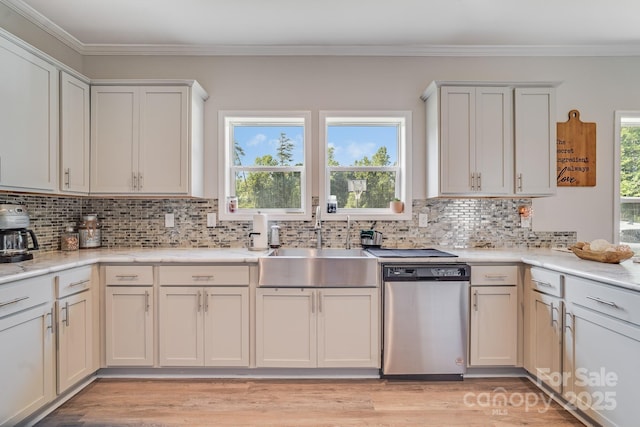 kitchen with light wood finished floors, white cabinets, dishwasher, ornamental molding, and a sink