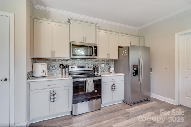 kitchen with decorative backsplash, ornamental molding, stainless steel appliances, and light countertops