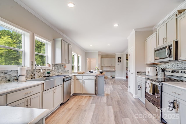 kitchen featuring a peninsula, stainless steel appliances, light countertops, light wood-type flooring, and a sink